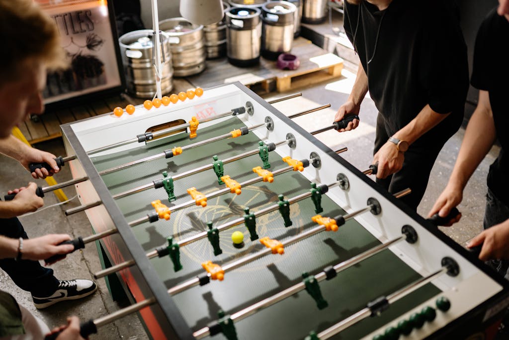 Energetic scene of people playing foosball indoors with vibrant colors and dynamic movement.